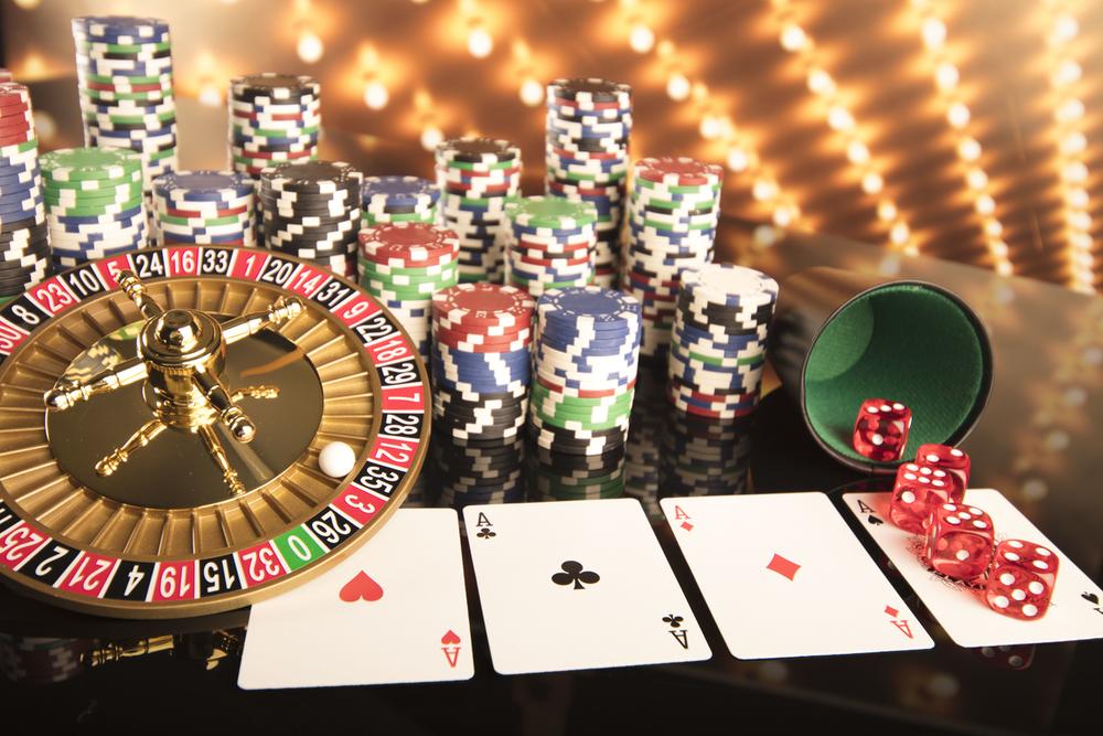 Roulette wheel, casino chips, playing cards and dice on a casino table